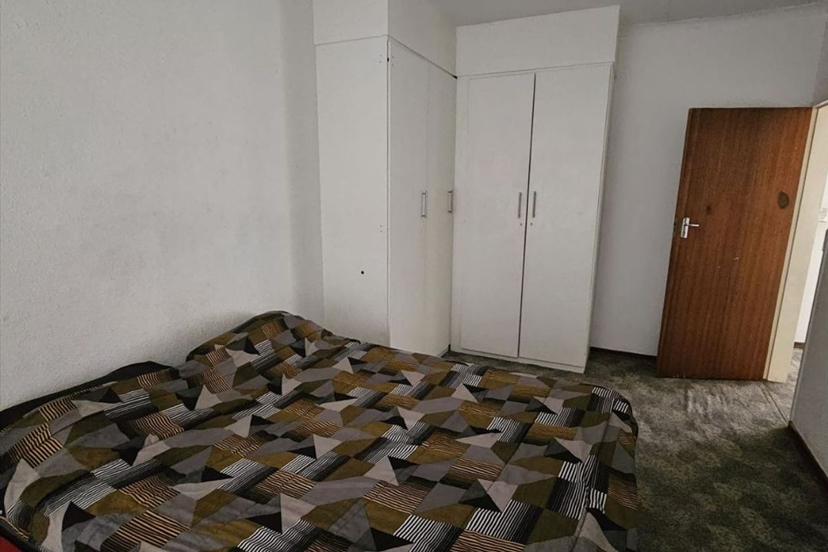 A bedroom featuring built-in cupboards and carpeted flooring, providing a functional space with standard finishes.