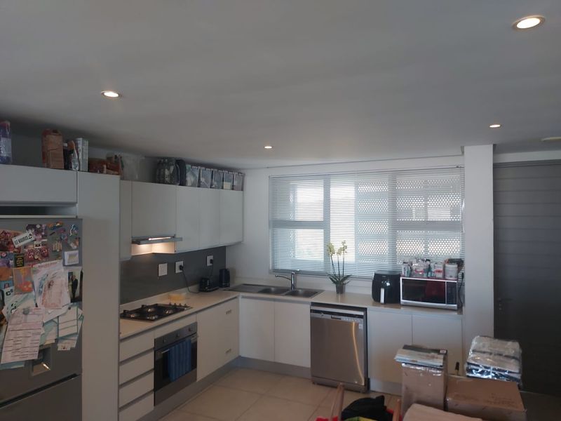 Modern kitchen featuring white cabinetry, gas hob, built-in oven, extractor fan, and stainless steel sink with tiled flooring and recessed lighting.