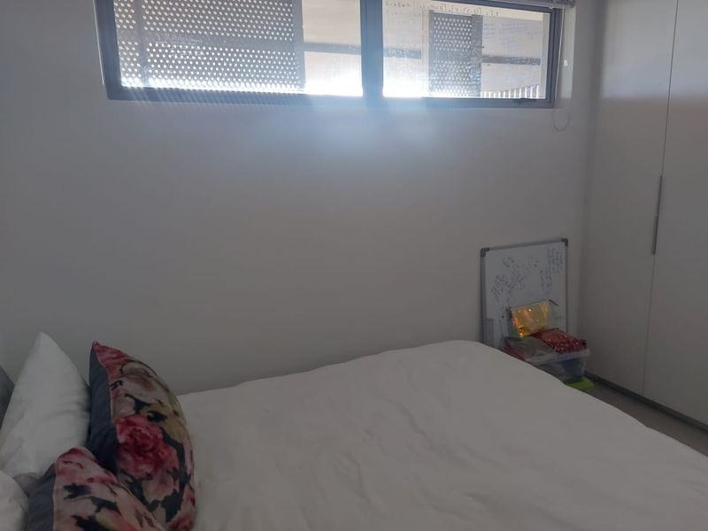 A bedroom featuring a built-in wardrobe and a horizontal window, providing natural light to the space.