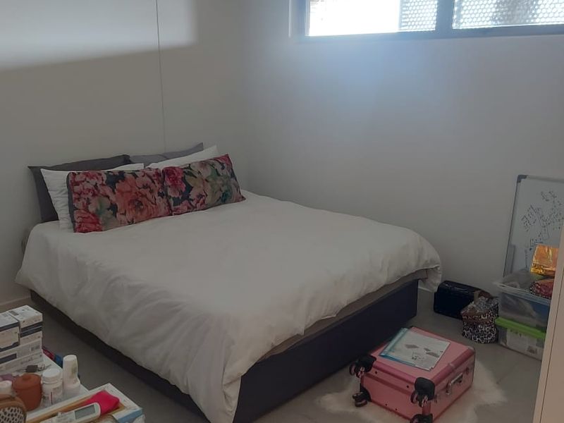 A functional bedroom featuring tiled flooring and a horizontal window, providing a neutral base for personalization.