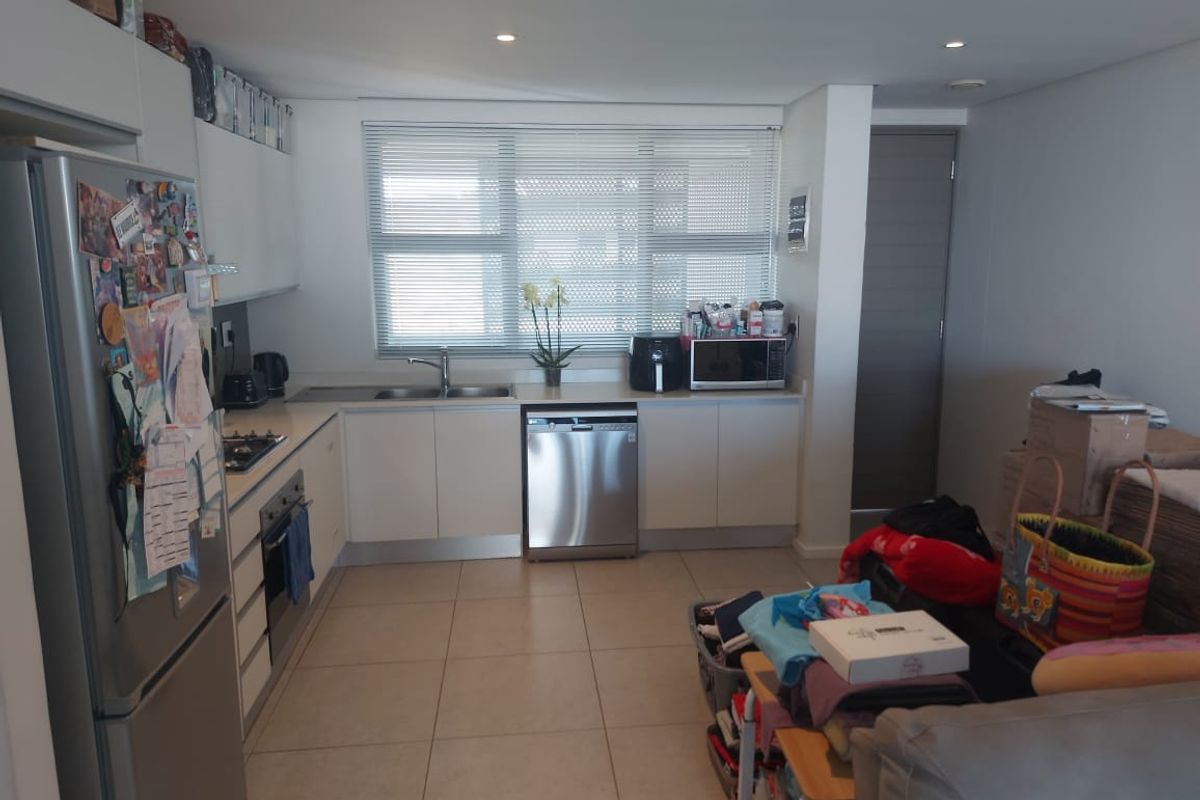 Modern kitchen featuring white cabinetry, stainless steel appliances, tiled flooring, and recessed lighting, offering a functional and clean workspace.