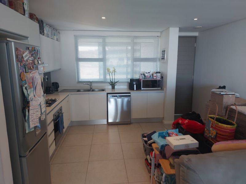 Modern kitchen featuring white cabinetry, stainless steel appliances, tiled flooring, and recessed lighting, offering a functional and clean workspace.