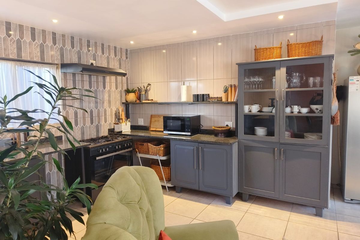 A well-maintained kitchen featuring dark grey cabinetry, granite countertops, a gas stove with extractor fan, and decorative tiled backsplash.