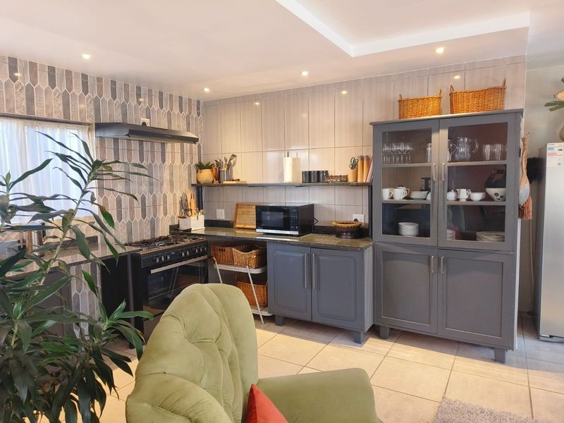 A well-maintained kitchen featuring dark grey cabinetry, granite countertops, a gas stove with extractor fan, and decorative tiled backsplash.