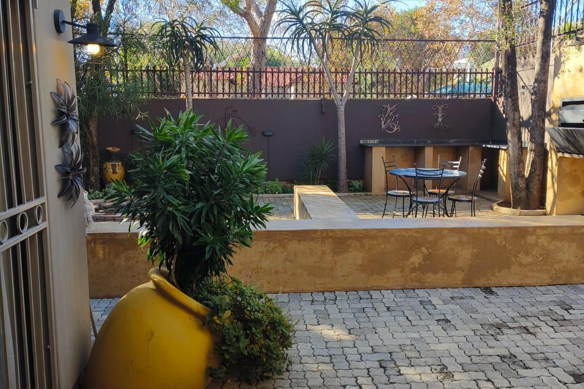 Rear courtyard featuring a paved patio area, built-in braai, and retaining wall, offering a private outdoor space for entertaining.
