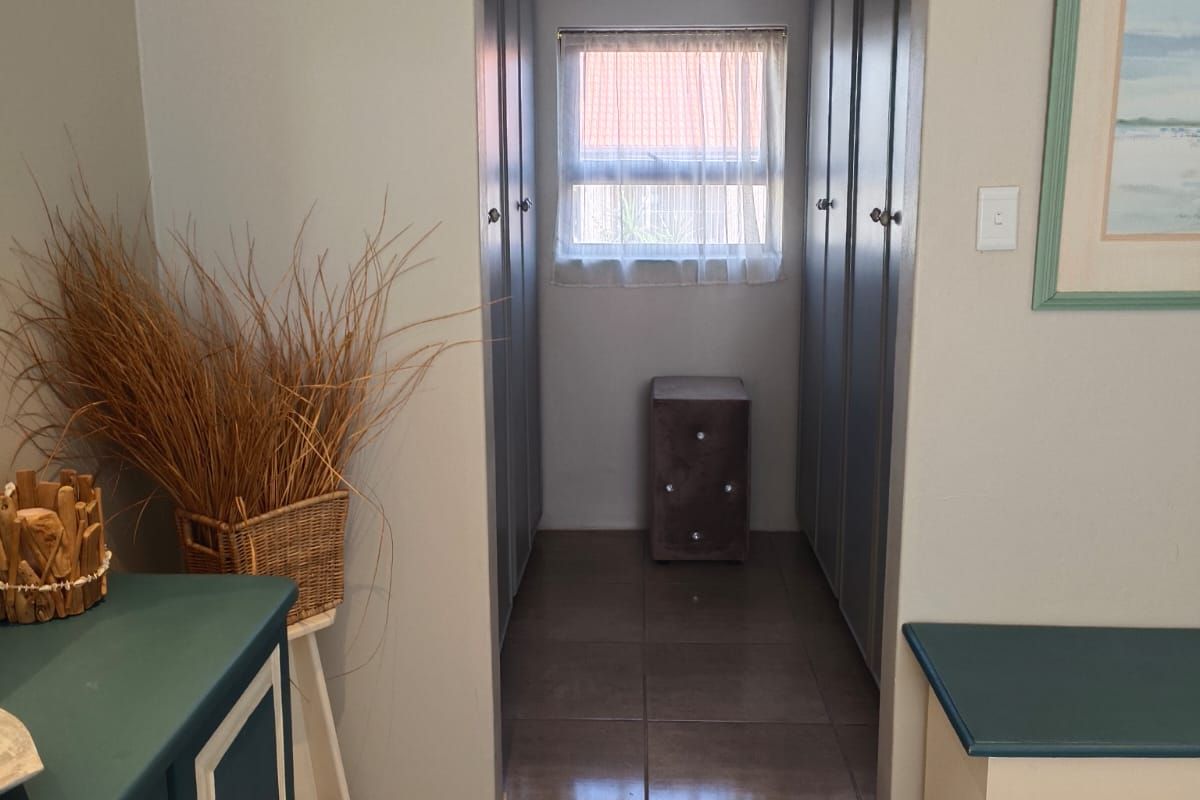 A bedroom featuring tiled flooring and a walk-in closet area with built-in cupboards and a window.