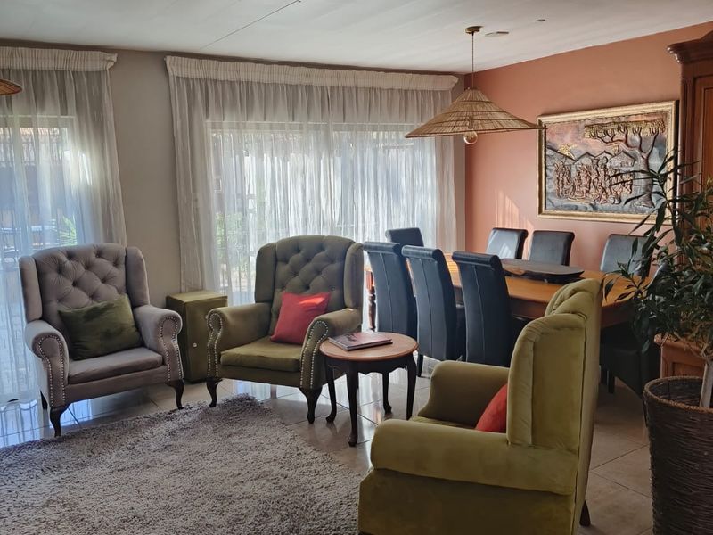 Spacious open-plan living and dining area featuring neutral tiled flooring and large windows with natural light.