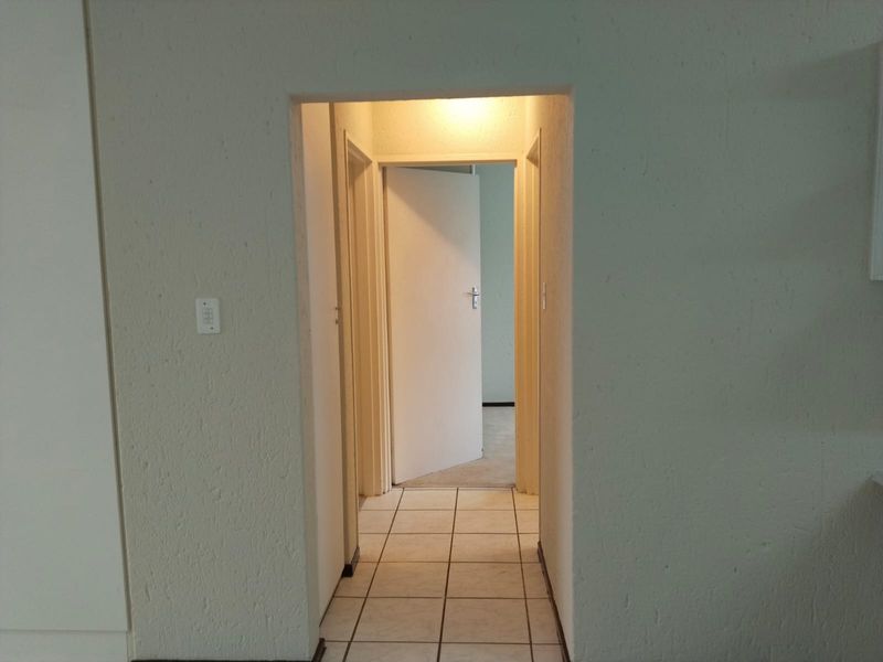 A functional hallway featuring tiled flooring and connecting multiple rooms within the townhouse.