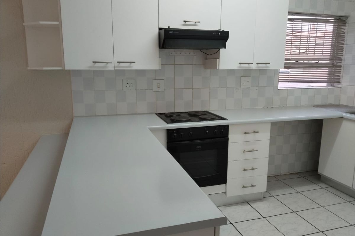 A clean and functional kitchen featuring white cabinetry, laminate countertops, a built-in oven with hob, and a tiled backsplash.