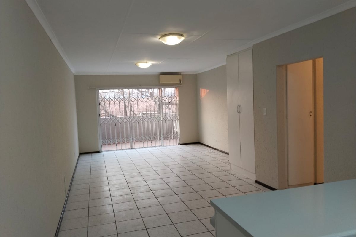 Spacious, empty living area featuring tiled flooring, a built-in cupboard, split-system air conditioning, and a sliding door leading to an outdoor space.