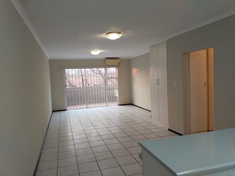 Spacious, empty living area featuring tiled flooring, a built-in cupboard, split-system air conditioning, and a sliding door leading to an outdoor space.