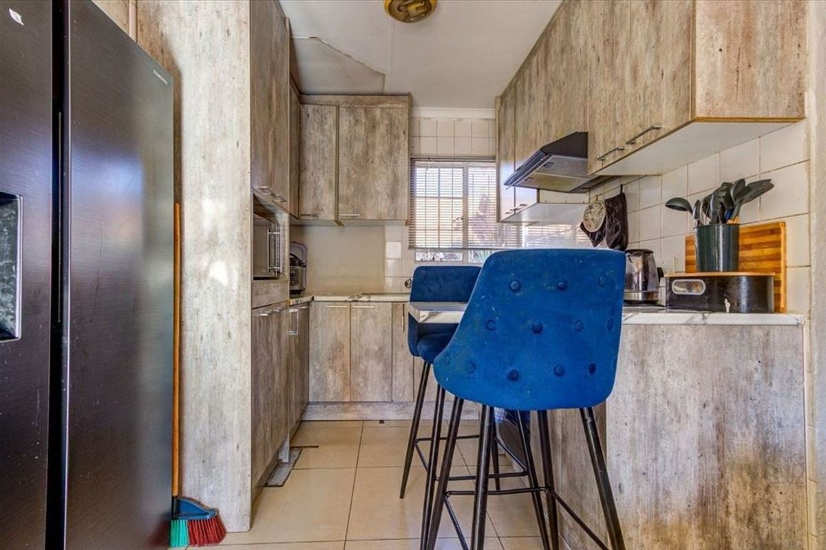 Compact kitchen featuring laminate cabinetry, tiled backsplash, and built-in appliances, showing visible signs of ceiling water damage requiring repair.