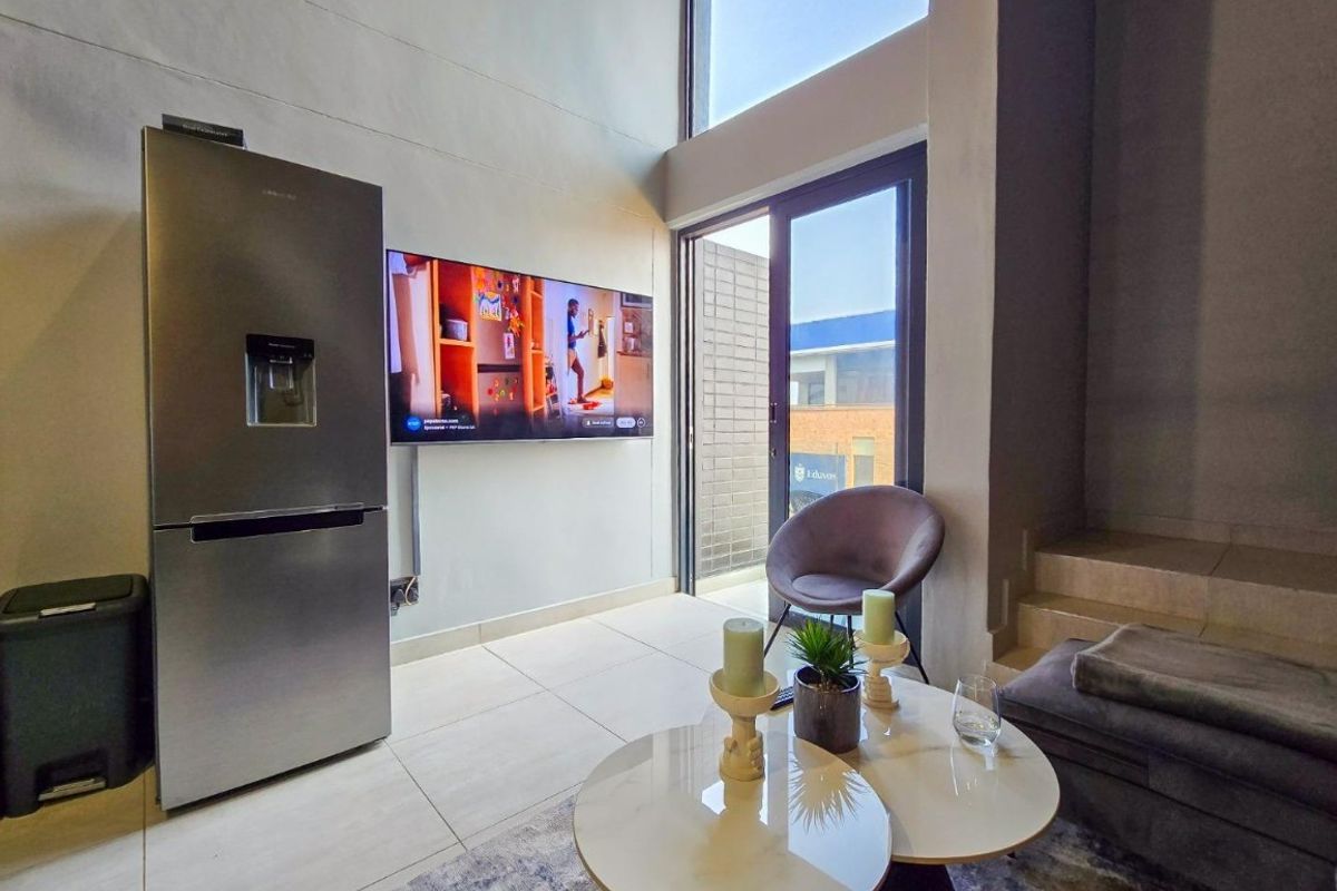 Modern living area featuring high ceilings, large windows for natural light, and direct access to an outdoor space through a sliding glass door.