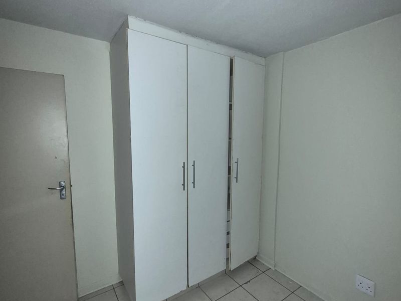 A vacant bedroom featuring tiled flooring and a built-in wardrobe, requiring minor cosmetic updates and fixture repairs.
