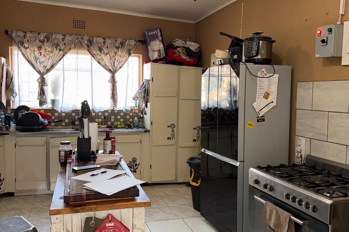 A functional kitchen featuring tiled flooring, a gas stove, built-in cabinetry, and a ceiling fan, offering potential for cosmetic updates to modernize the space.