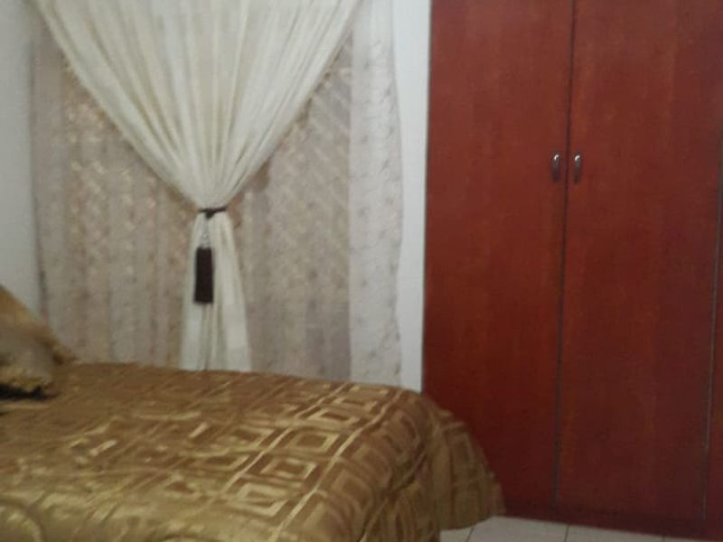 A bedroom featuring tiled flooring and a full-height built-in wooden wardrobe.