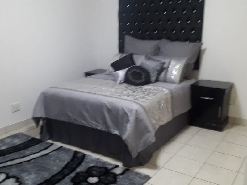 A simple bedroom featuring neutral wall finishes and tiled flooring, providing a functional space for rest.