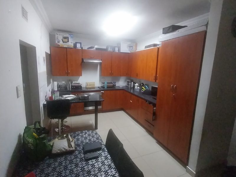 A functional kitchen featuring wood-tone cabinetry, dark countertops, built-in oven, and extractor fan, with tiled flooring and decorative ceiling coving.