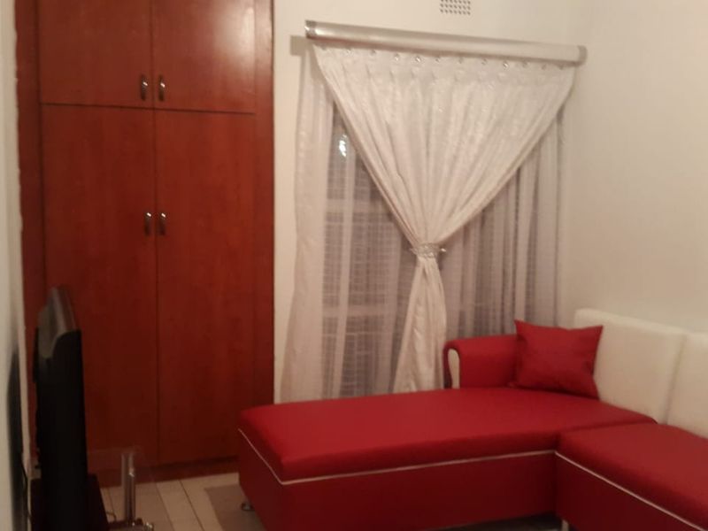 A bedroom featuring a built-in wooden wardrobe and a window with installed curtain rails.