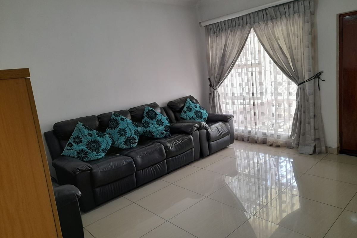 A living room featuring neutral tiled flooring and decorative ceiling cornicing, providing a clean and functional space.