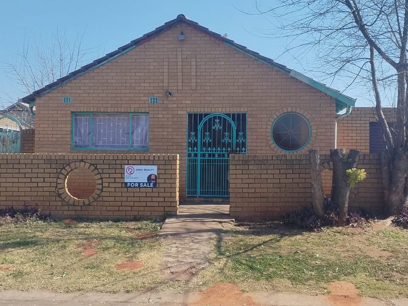 Front elevation of a single-story brick house featuring a tiled roof, security gates, and an attached garage with a paved driveway.