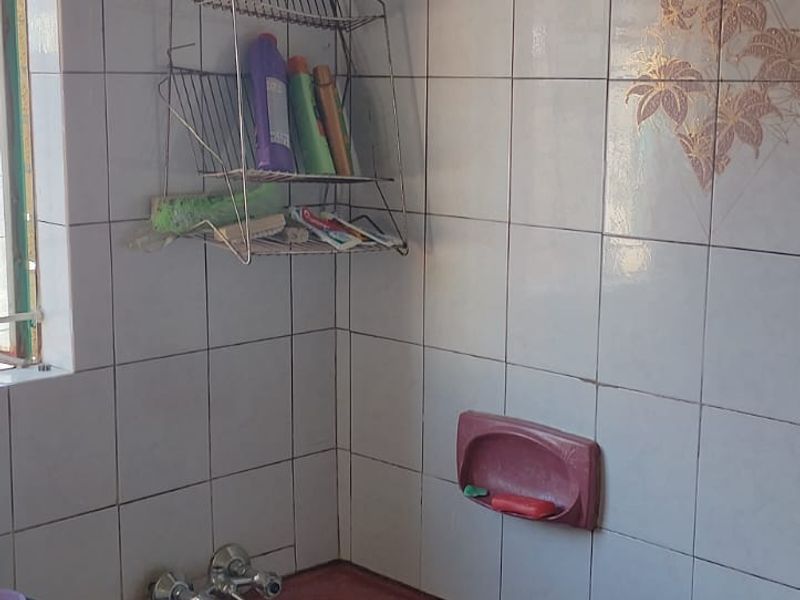 A dated bathroom featuring a built-in bathtub with wall tiling and standard plumbing fixtures, offering potential for a modern renovation.