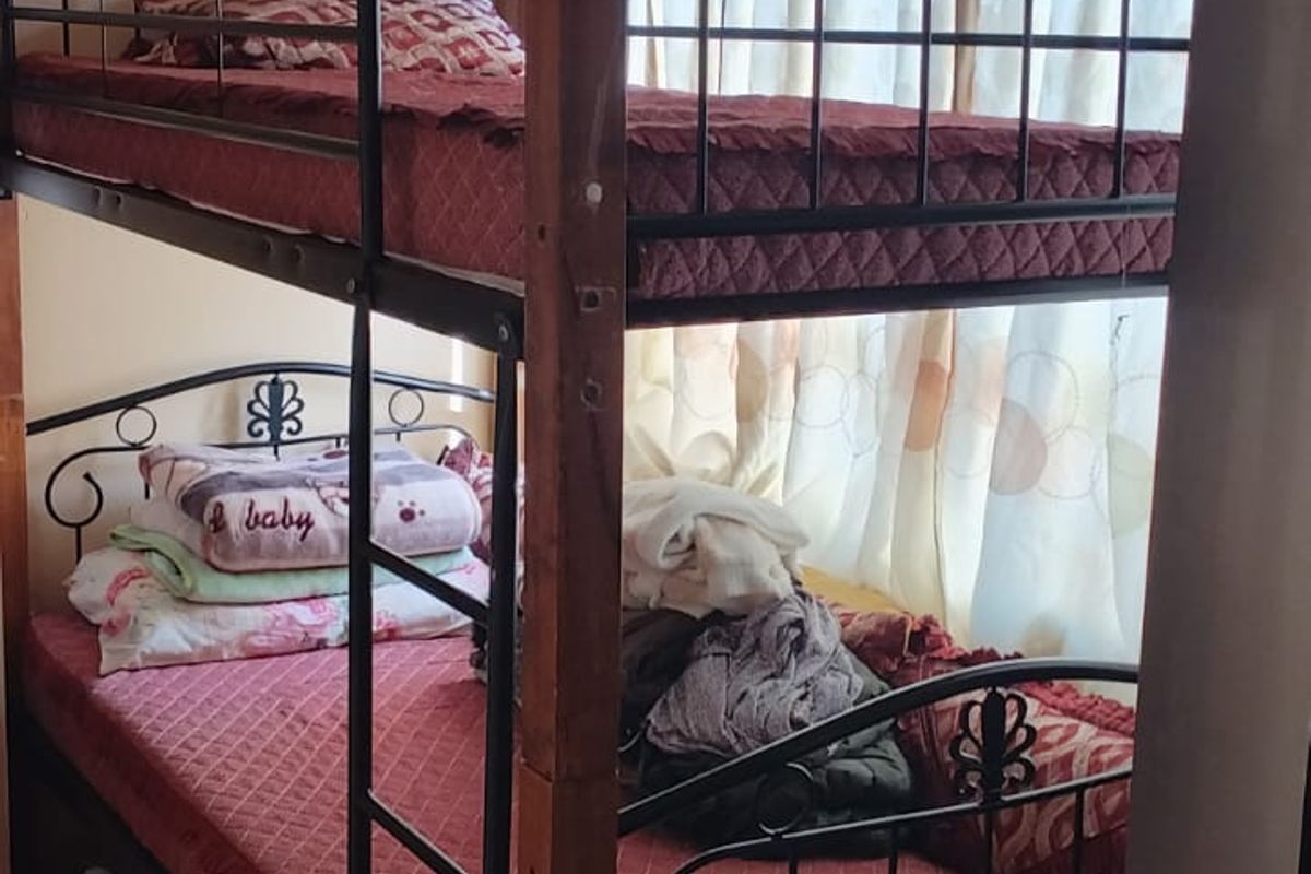 A bedroom featuring a bunk bed setup with visible signs of ceiling wear and water staining requiring maintenance.