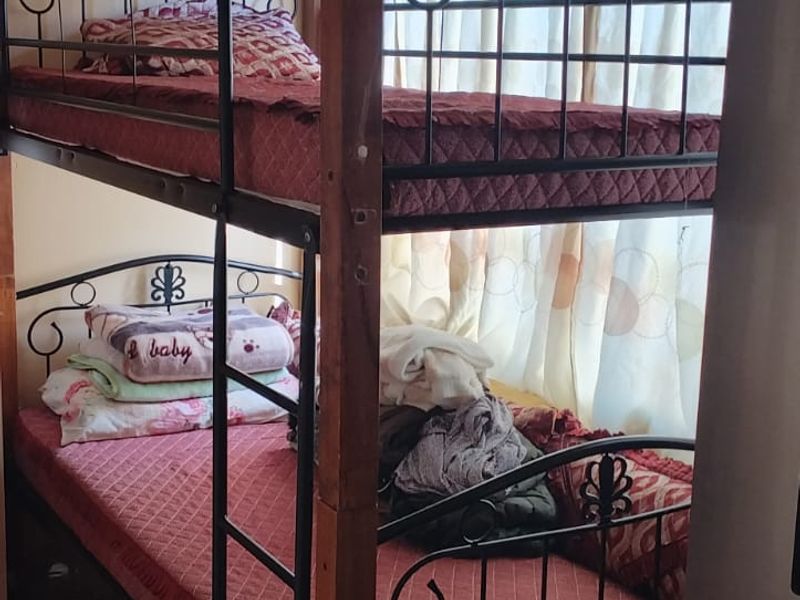 A bedroom featuring a bunk bed setup with visible signs of ceiling wear and water staining requiring maintenance.