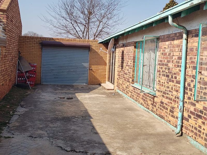 Rear exterior view of the property featuring a concrete driveway, brick facade, and a roller shutter garage door.