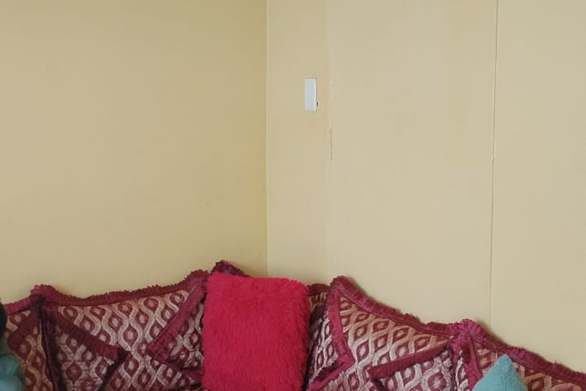 A corner view of a living room featuring plain walls and ceiling coving, requiring cosmetic updates to improve the overall aesthetic.