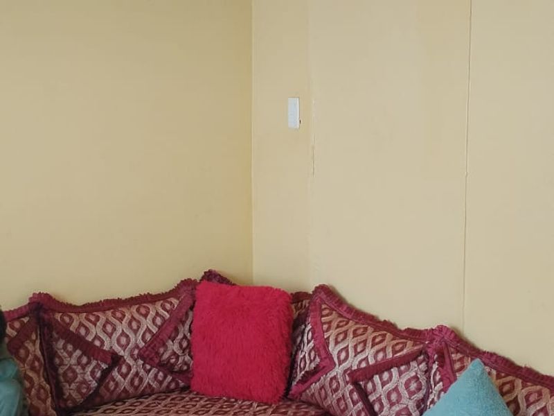 A corner view of a living room featuring plain walls and ceiling coving, requiring cosmetic updates to improve the overall aesthetic.