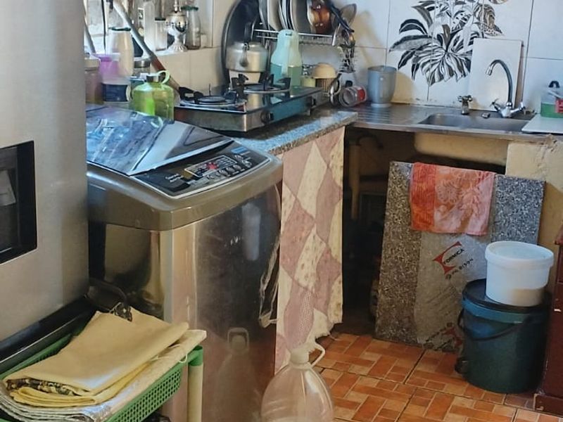 A compact kitchen featuring built-in cabinetry, a tiled backsplash, and a stainless steel sink, requiring modernization to improve functionality and aesthetic appeal.