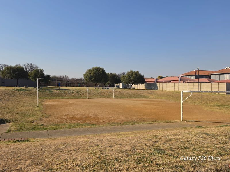 Outdoor communal sports field featuring goal posts and a paved walkway within a residential complex.