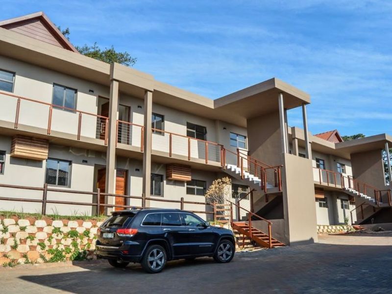 A modern multi-story apartment complex featuring paved driveway access, external staircases, and balcony railings with a well-maintained facade.