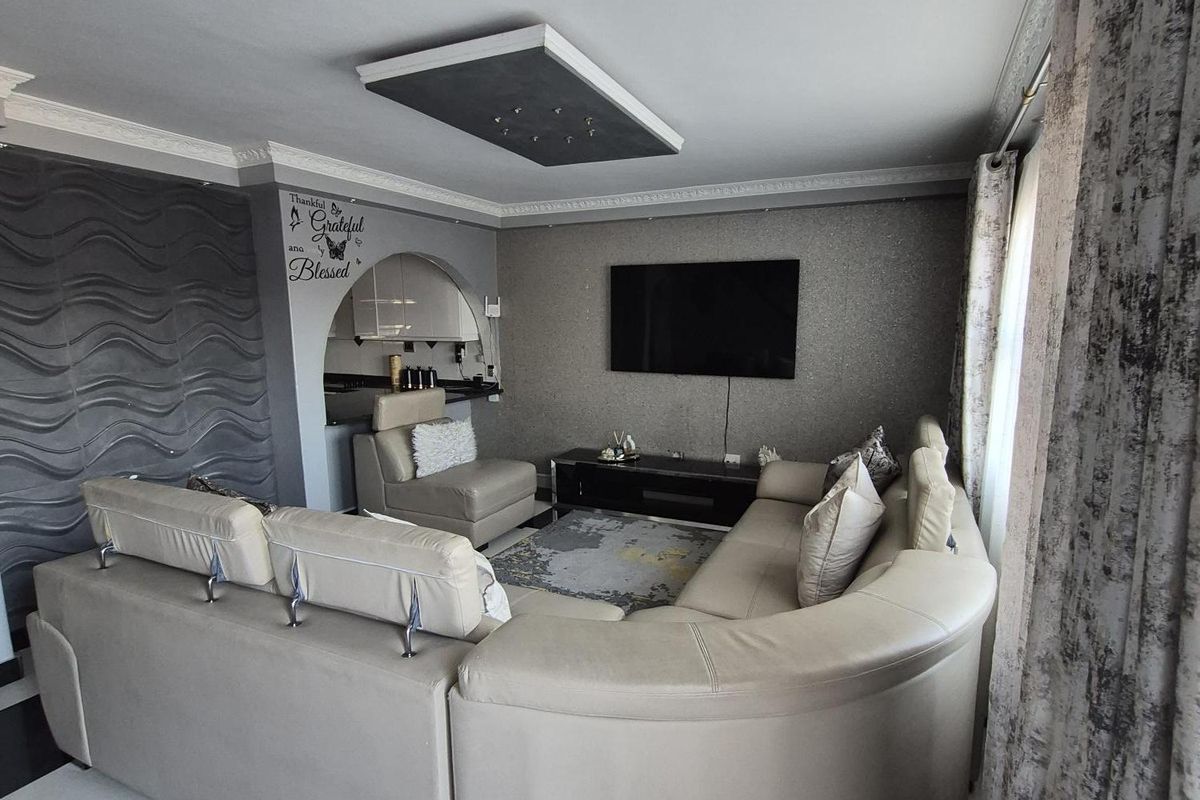 A living room featuring a textured accent wall, a unique recessed ceiling detail, and high-contrast checkered floor tiles.