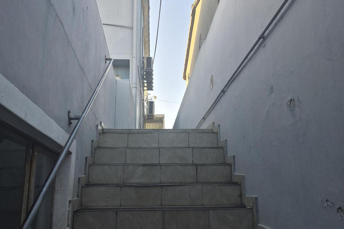 An exterior staircase leading between two building structures, featuring tiled steps and metal handrails.