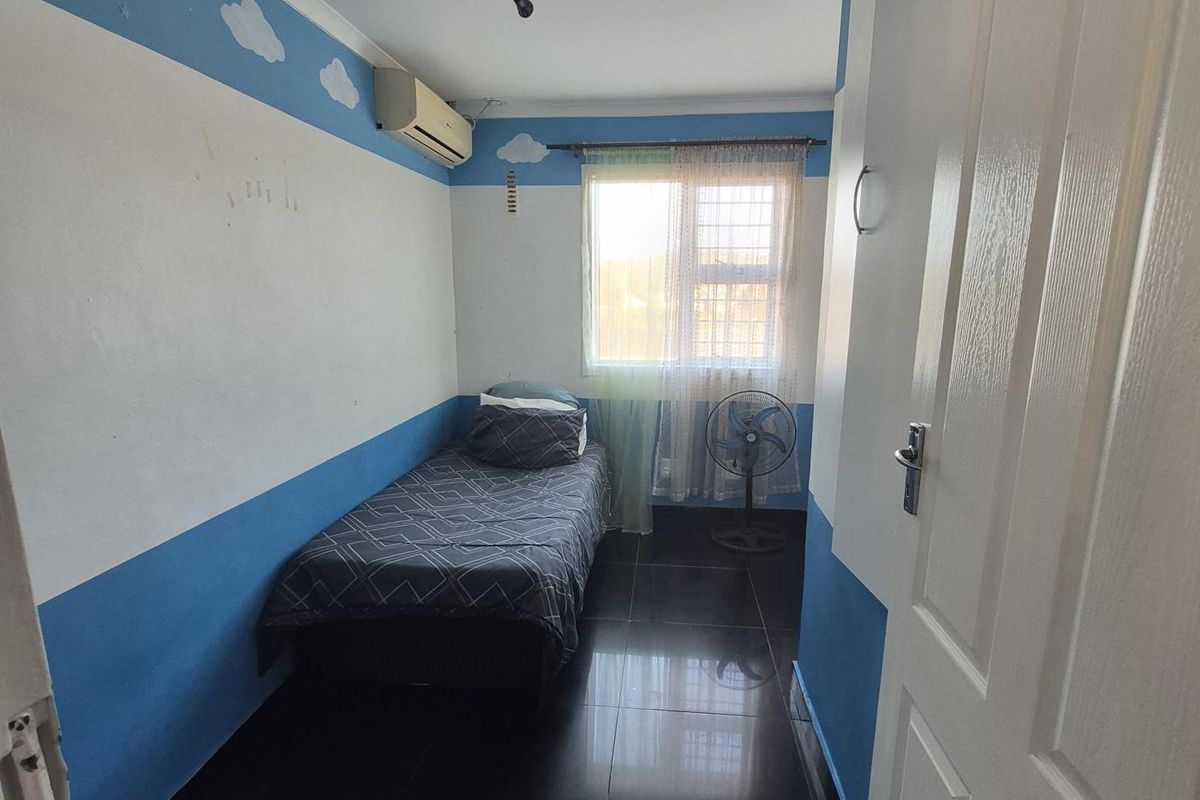 A compact bedroom featuring dark tiled flooring, an air conditioning unit, and decorative wall painting.