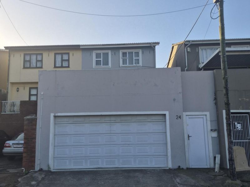 Front elevation of the property featuring a single garage door, pedestrian entrance, and concrete driveway.