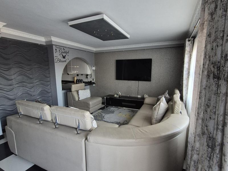 A living room featuring a textured accent wall, a unique recessed ceiling detail, and high-contrast checkered floor tiles.