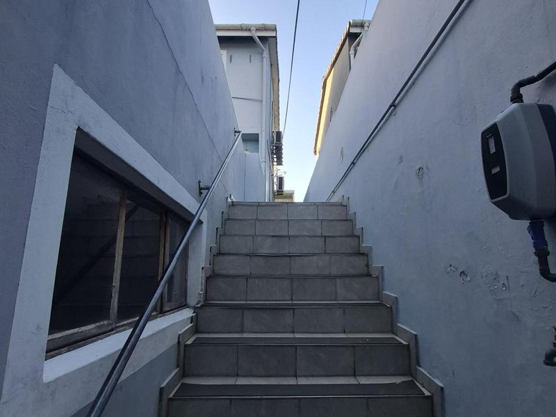 An exterior staircase with tiled steps and a metal handrail leading between two building sections.