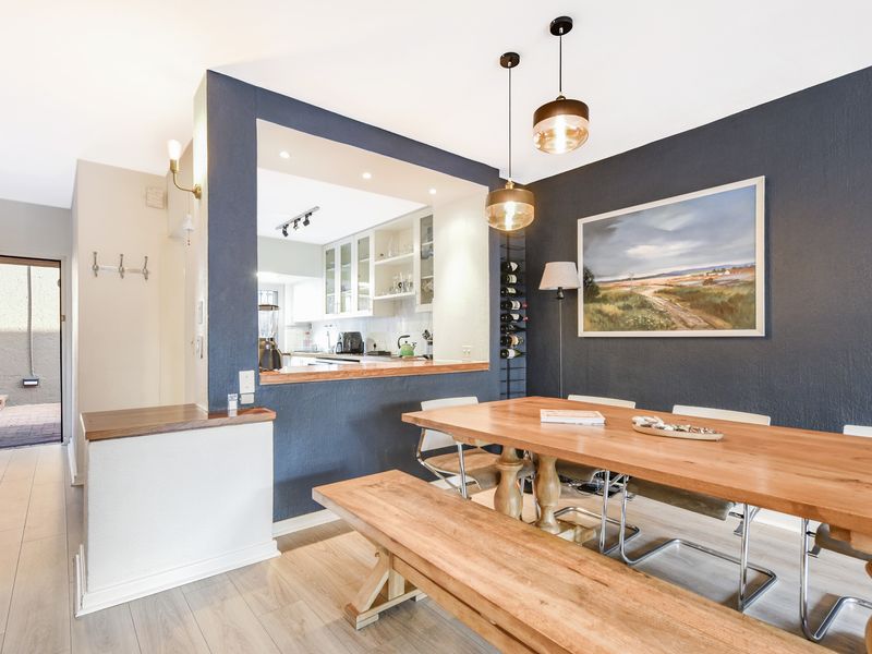 Open plan dining area featuring modern pendant lighting, dark accent wall, and a convenient pass-through window connecting to the kitchen.