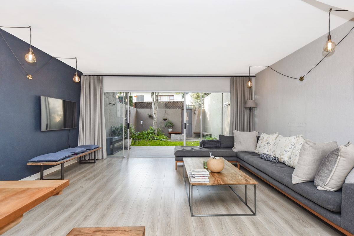Spacious living room featuring modern laminate flooring, feature accent wall, and large sliding glass doors providing seamless access to the rear garden area.