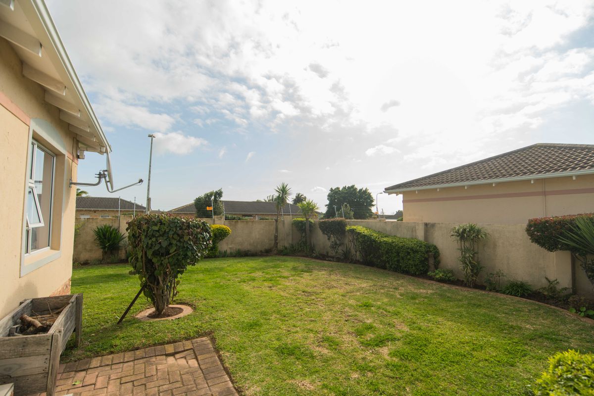 A private rear garden featuring a lawn, paved patio area, and perimeter walling, providing a functional outdoor space for the townhouse.