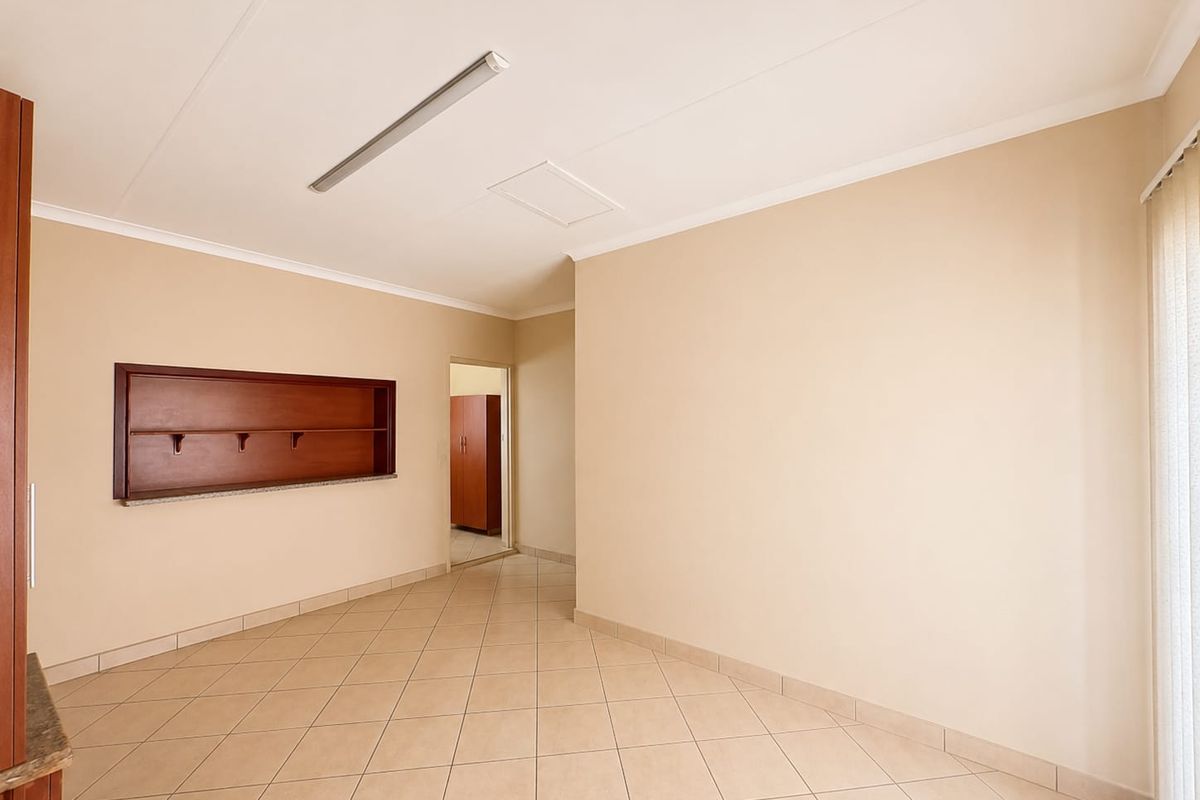 An empty living area featuring neutral tiled flooring, built-in wall shelving, and a simple ceiling light fixture, offering a clean canvas for interior design.