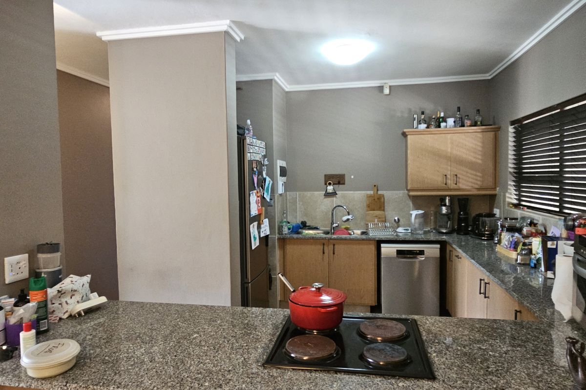 Functional kitchen featuring granite countertops, built-in cabinetry, an electric hob, and an integrated dishwasher, offering a practical layout for daily use.