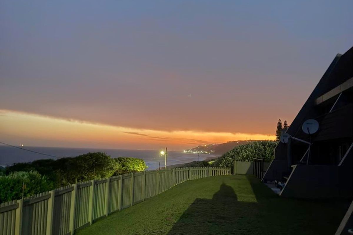 A scenic evening view overlooking the coastline, featuring perimeter fencing and exterior lighting at dusk.