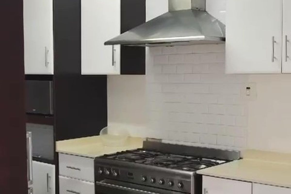 Modern kitchen featuring white cabinetry, stone countertops, a subway tile backsplash, and a stainless steel gas stove with an integrated extractor fan.