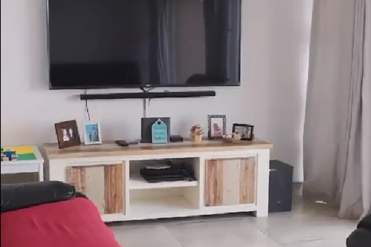 A living room area featuring neutral tiled flooring and wall-mounted television setup.