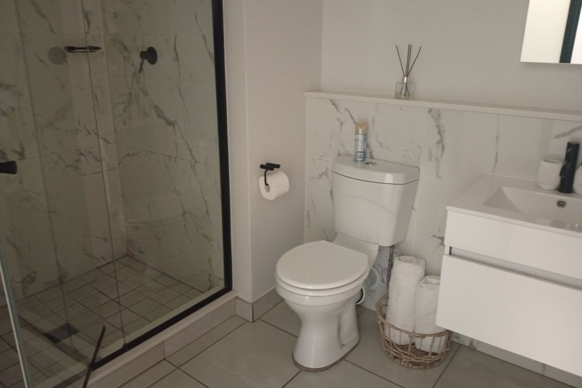 Modern bathroom featuring a walk-in shower with marble-look tiling, a wall-mounted vanity, and contemporary black fixtures.