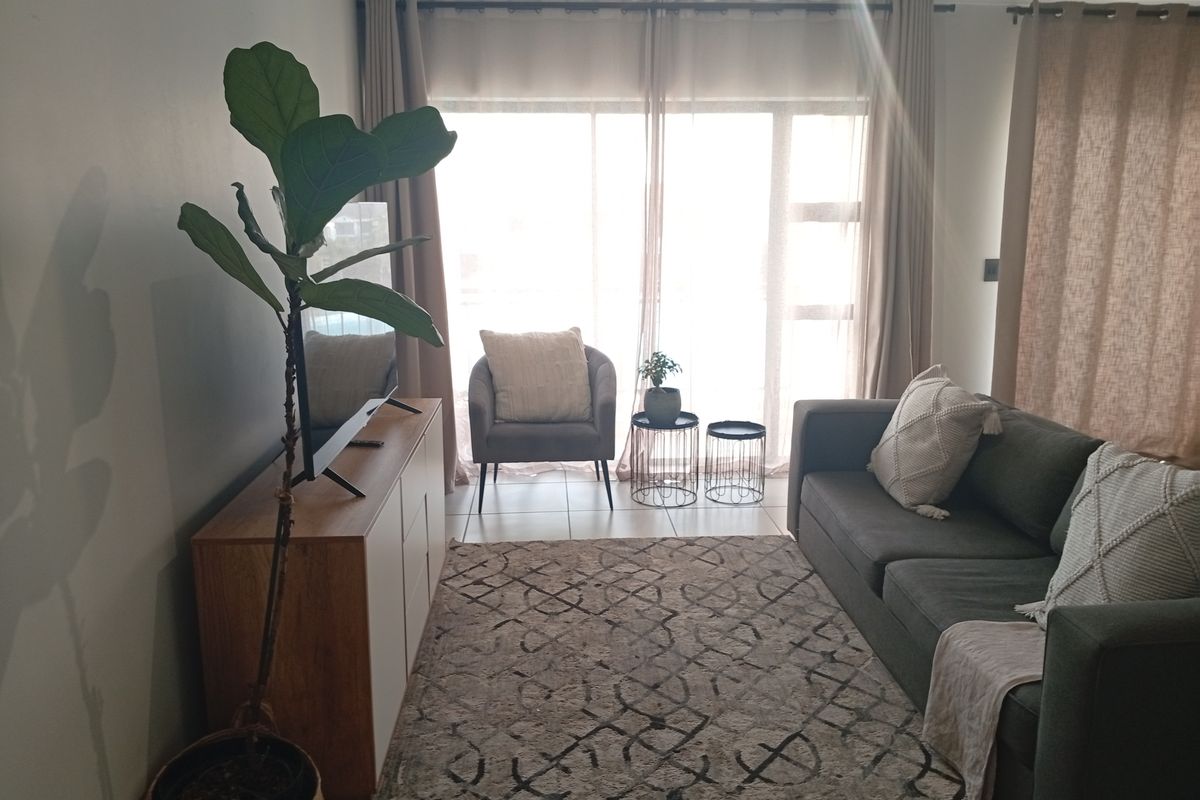 A comfortable living room featuring tiled flooring and a large sliding glass door that provides natural light.